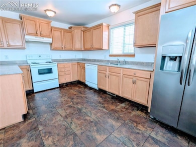 Kitchen featuring light brown cabinetry, white appliances, under cabinet range hood, and light countertops