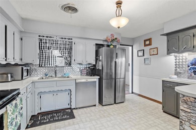 Kitchen with tasteful backsplash, stainless steel appliances, sink, gray cabinets, and decorative light fixtures