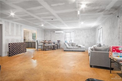 Living area featuring finished concrete floors and an AC wall unit