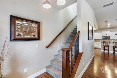 Stairs featuring hardwood / wood-style floors and vaulted ceiling