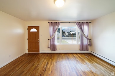 Entrance foyer with wood-type flooring and a baseboard heating unit