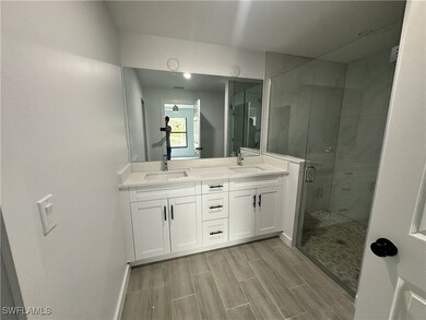 Bathroom with wood finish floors, a sink, a shower stall, and double vanity