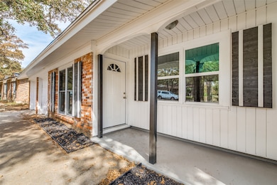 View of exterior entry with board and batten siding, a porch, and brick siding