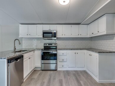 Kitchen featuring light stone counters, sink, whit