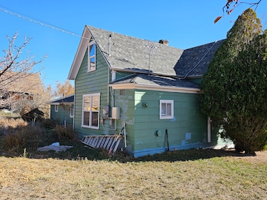 View of side of home with a chimney, a shingled roof, and a lawn