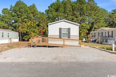 Manufactured / mobile home featuring a deck, board and batten siding, and view of scattered trees