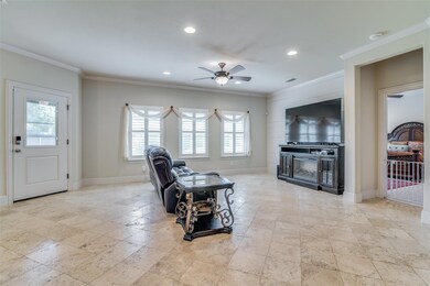 Living room with crown molding, ceiling fan, and plenty of natural light