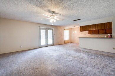 Unfurnished living room with ceiling fan, french doors, a textured ceiling, and light colored carpet