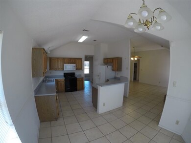 Kitchen featuring ceiling fan with notable chandelier, white appliances, vaulted ceiling, and hanging light fixtures
