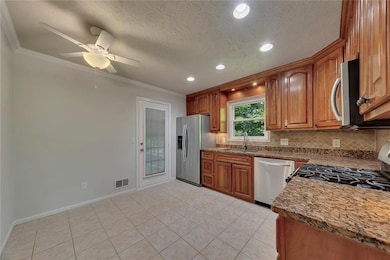 Kitchen with ornamental molding, backsplash, stainless steel appliances, brown cabinetry, and recessed lighting
