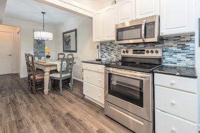 Kitchen with white cabinetry, linear glass tile ba