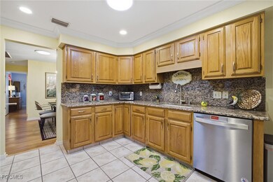 Kitchen featuring light stone counters, dishwasher, tasteful backsplash, crown molding, and light tile patterned flooring