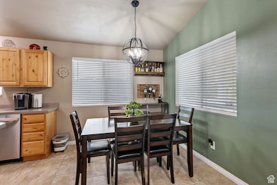 Dining room with a chandelier, light tile patterned floors, and lofted ceiling