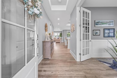 Corridor featuring light wood finished floors, a skylight, recessed lighting, and french doors