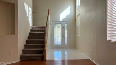 Tiled entrance foyer featuring stairs and a textured wall