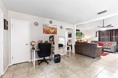 Living room featuring light tile patterned flooring, an office area, a textured ceiling, lofted ceiling, and a ceiling fan