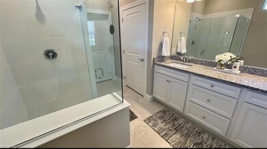 Bathroom featuring vanity, walk in shower, and til