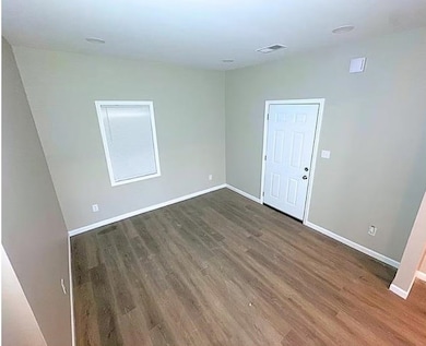 Spare room with dark wood-type flooring and baseboards