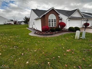 View of front of property with a front lawn, brick siding, a garage, and driveway