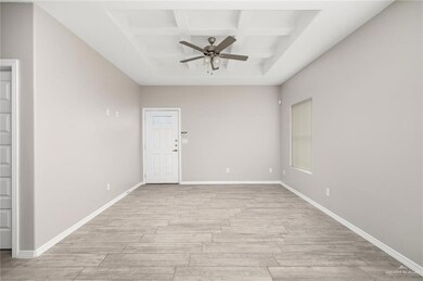 Empty room with coffered ceiling, light wood-style floors, ceiling fan, and beamed ceiling
