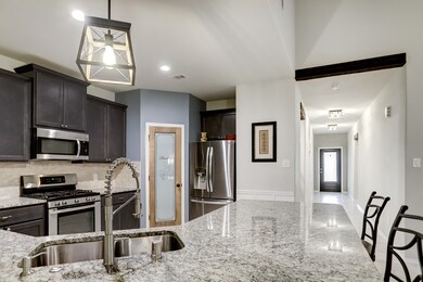 Main hallway leads to the tiled kitchen with versatile granite countertops, stone subway tile and a corner pantry featuring a custom frosted glass door.