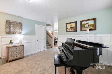 Sitting room with a decorative wall, a wainscoted wall, a textured ceiling, carpet flooring, and stairway