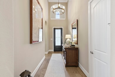This is a welcoming entryway with high ceilings, featuring a stylish chandelier and an abundance of natural light. 