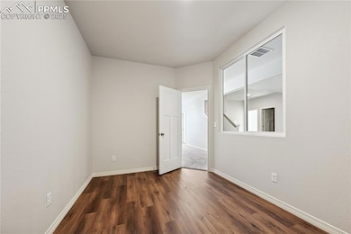 Unfurnished room featuring dark wood-type flooring and baseboards