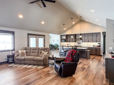 Living room with light wood finished floors, high vaulted ceiling, ceiling fan, and recessed lighting