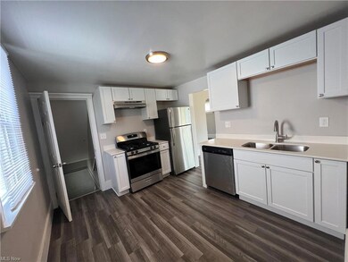 Kitchen with white cabinets, appliances with stainless steel finishes, light countertops, and dark hardwood floors