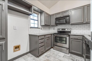 Kitchen with electric stove, dark stone counters, 