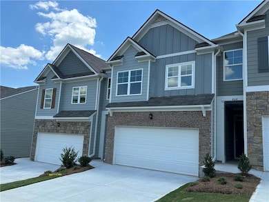 View of front of house featuring board and batten siding, driveway, a garage, and stone siding