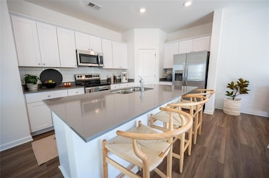 Kitchen featuring appliances with stainless steel finishes, a sink, baseboards, an island with sink, and recessed lighting