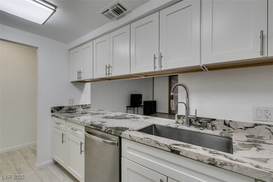 Kitchen with dishwasher, a sink, white cabinets, l