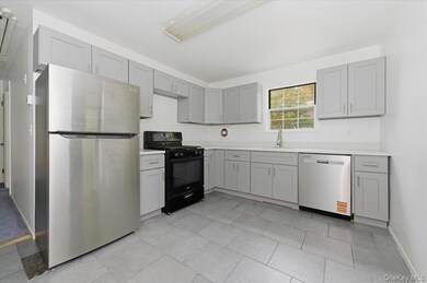 Kitchen with stainless steel appliances, gray cabinets, and light tile patterned flooring