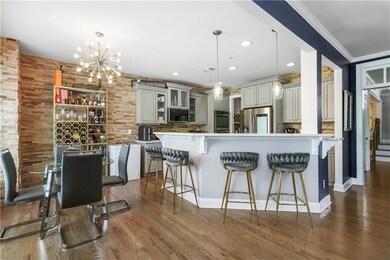 Kitchen featuring stainless steel appliances, a kitchen breakfast bar, recessed lighting, a chandelier, and glass insert cabinets