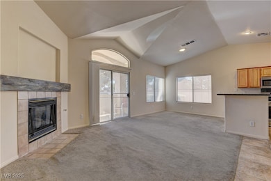 Unfurnished living room with vaulted ceiling, light carpet, and a fireplace