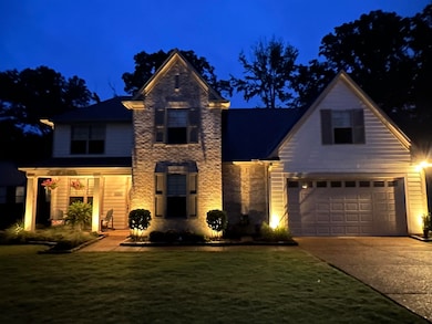 Traditional home featuring a garage, driveway, a lawn, and stone siding
