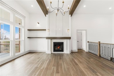Unfurnished living room featuring beamed ceiling, a high ceiling, and wood finished floors