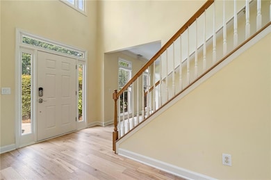Entryway with plenty of natural light, wood finished floors, a towering ceiling, and stairway