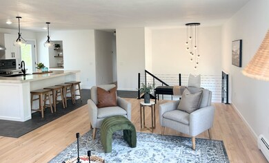 Sitting room featuring baseboard heating, an upstairs landing, light wood-style flooring, and baseboards