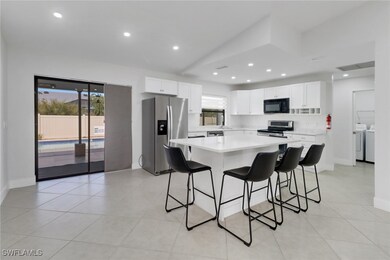 Kitchen featuring separate washer and dryer, a kitchen breakfast bar, a kitchen island, stainless steel appliances, and white cabinets