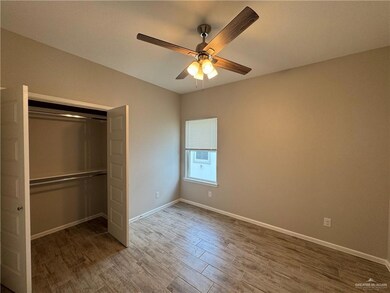 Unfurnished bedroom featuring wood finished floors, baseboards, a closet, and a ceiling fan