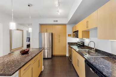 Kitchen with a sink, light brown cabinetry, dark s