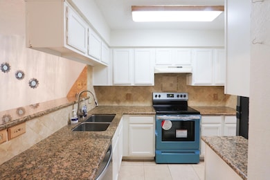 Kitchen featuring under cabinet range hood, a sink
