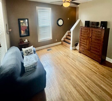 Living area featuring light wood finished floors, stairway, and ceiling fan