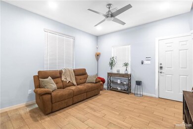 Living area featuring a ceiling fan, light wood-style flooring, and baseboards