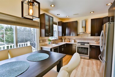 Kitchen featuring dark brown cabinets, wall chimney exhaust hood, appliances with stainless steel finishes and sliders to the outside