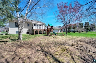 Rear view of property with a playground, a yard, a