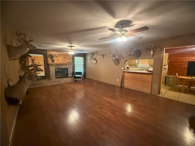 Living room with ceiling fan, a fireplace, and lig